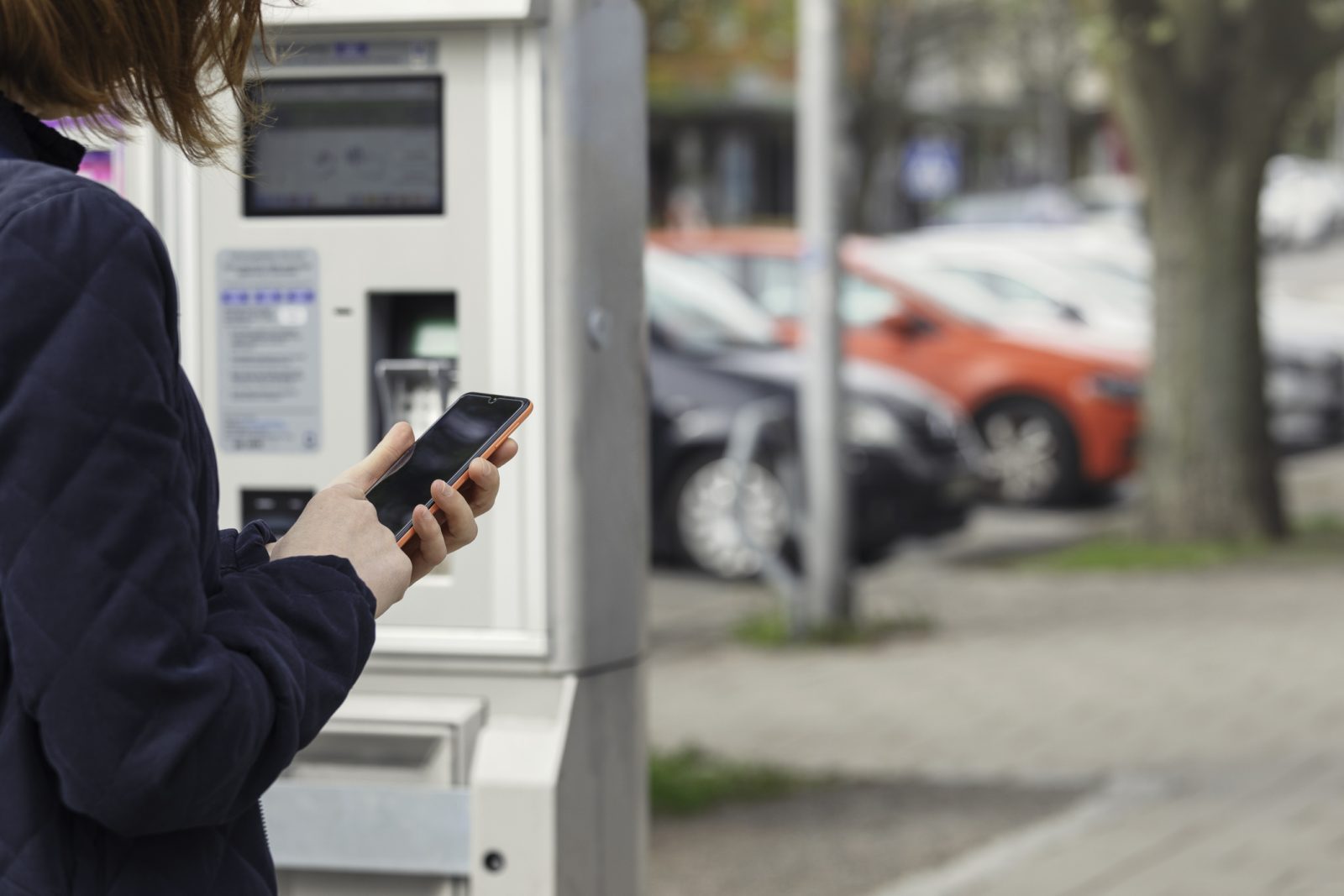 Person der betaler for parkering via sin smartphone foran en automat – APCOA PARKING kundecase