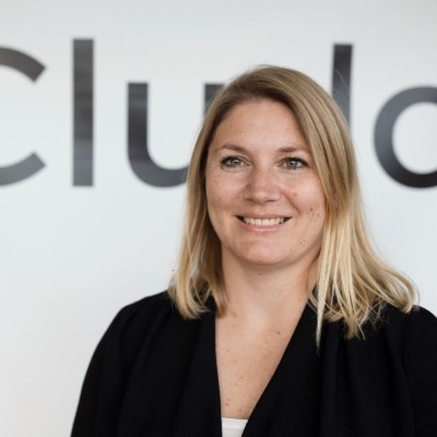 Portræt af Anna Mette Olsen, Sales Operations Manager hos Cludo, foran et Cludo-logo på væggen i forbindelse med hendes udtalelse om Corpital.