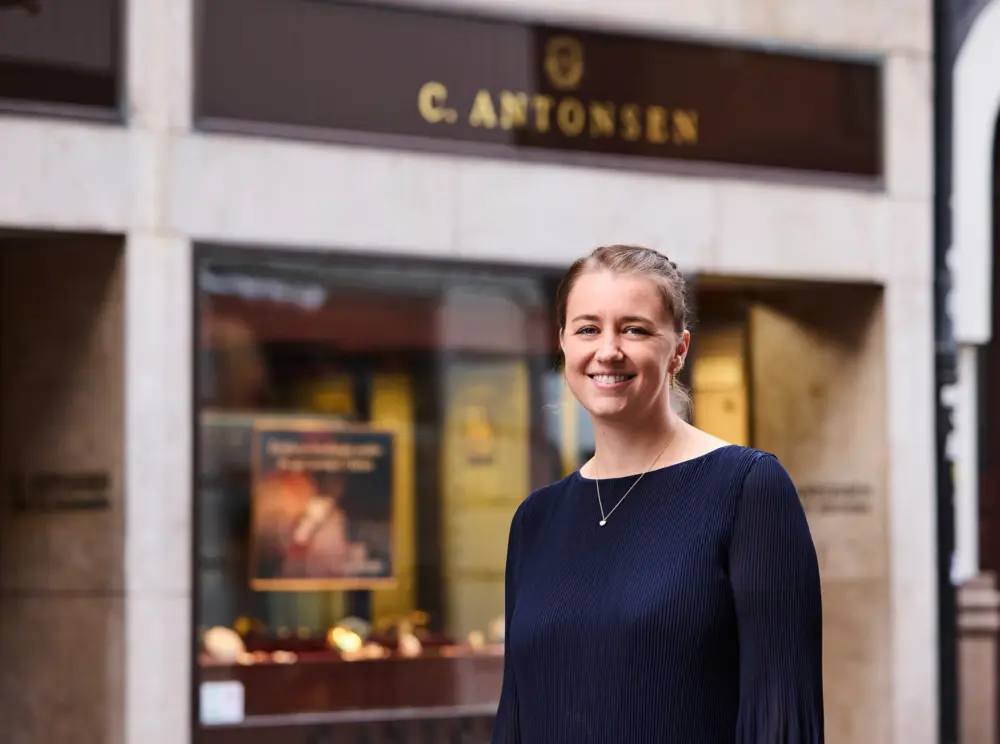 Else-Marie Schjerning står smilende foran sin forretning, Guldsmed C. Antonsen i Odense