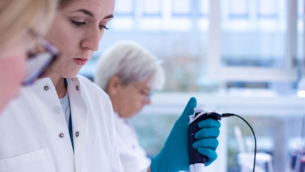 Laborant hos Immudex anvender automatisk pipette til præcisionsmålinger under kvalitetssikring af bioteknologiske produkter.